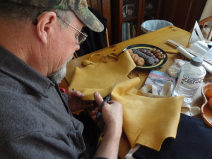 Steve B. carefully cuts out his moccasin pieces from an elk hide.